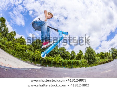 Stock photo: Boy Riding A Scooter Going Airborne