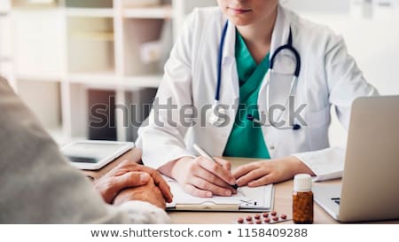 Stock photo: Portrait Of Young Male Doctor Writing On A Patients Medical Cha