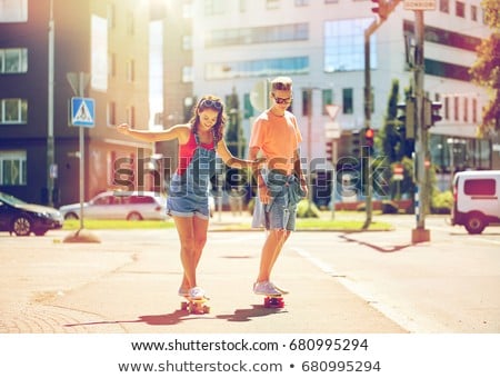 Stockfoto: Teenage Couple Riding Skateboards On City Street