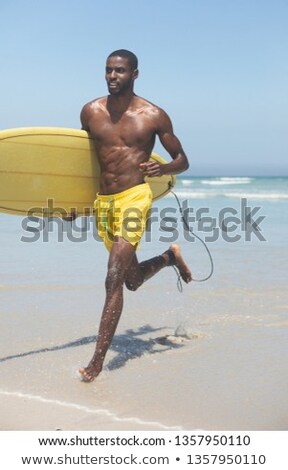 Stockfoto: Front View Of Handsome Fit African American Male Surfer With Yellow Surfboard Running Out Of The Sea