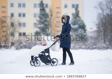 Stock photo: Young Mother With Baby In Stroller Walks Street Winter