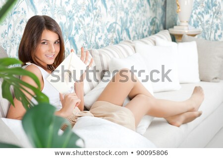 Foto stock: Delighted Woman Reading A Greeting Card Sitting On The Sofa At H