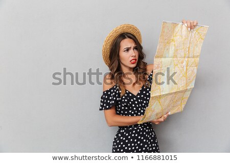 Сток-фото: Shocked Young Woman Wearing Hat Holding Map Over Grey Wall