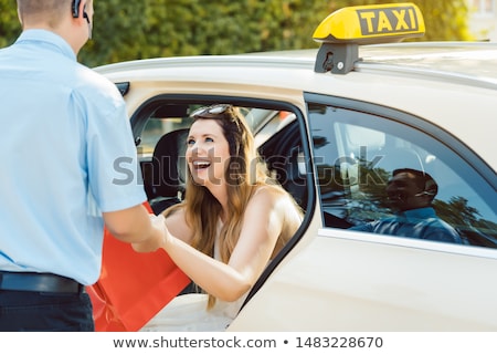 Foto d'archivio: Taxi Driver Helping Woman Passenger Out Of The Car