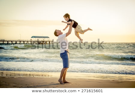 Zdjęcia stock: Young Happy Father Holding Up In His Arms Little Son Putting Him Up At The Beach Waves Wet Sand Havi