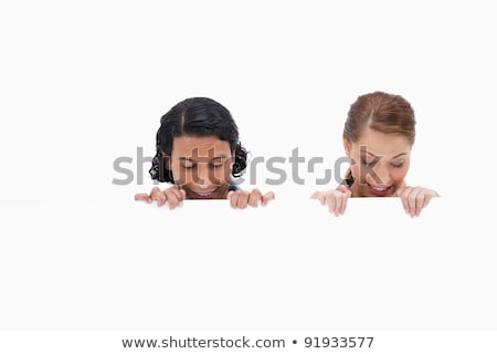 Stock photo: Cheerful Couple Looking Down On Blank Wall Against A White Background