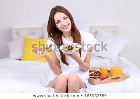 Foto stock: Portrait Of Young Woman Holding Cookie And Fruit Bowl