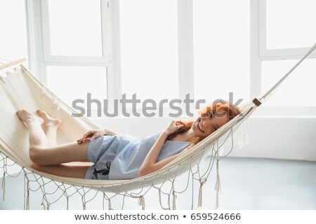 Foto d'archivio: Cute Cheerful Young Redhead Lady Lies On Hammock