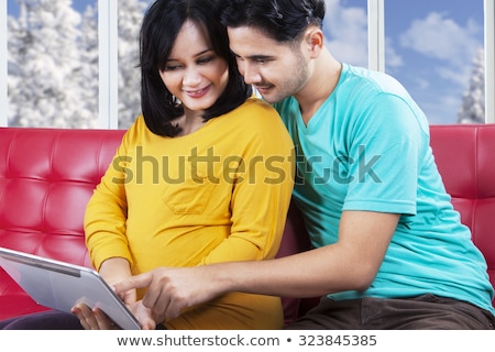 Foto d'archivio: Happy Pregnant Asian Woman With Tablet Pc At Home