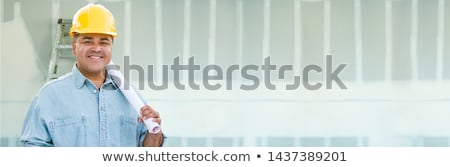 Foto stock: Hispanic Male Contractor Wearing Hard Hat Against Drywall Banner