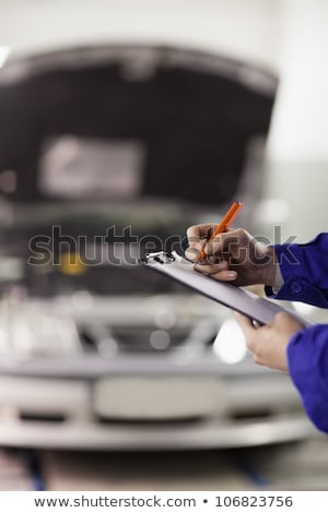 Stock foto: Focus On A Man Writing On A Clipboard In A Garage