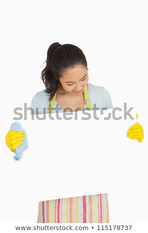 Stok fotoğraf: Happy Woman In Rubber Gloves And Apron Looking At White Surface She Is Holding