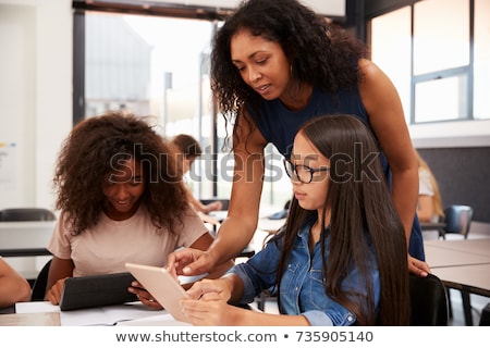 Stock foto: In · Lehrer · spricht · mit · einem · Schüler, · der · einen · Computer · in · einer · High · School · benutzt