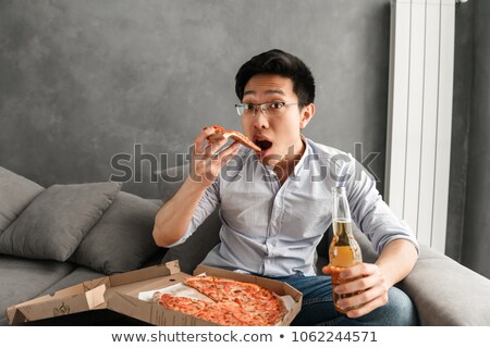 ストックフォト: Portrait Of A Scared Young Asian Man Eating Pizza