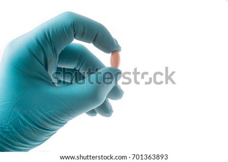 Foto stock: Hand With Green Protective Glove Holding An Oblong Pill