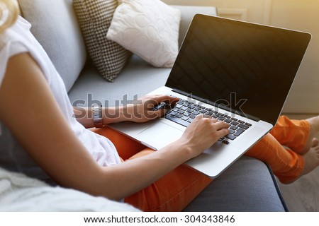 Stockfoto: Casual Young Woman Lying On Couch And Using Laptop At Home