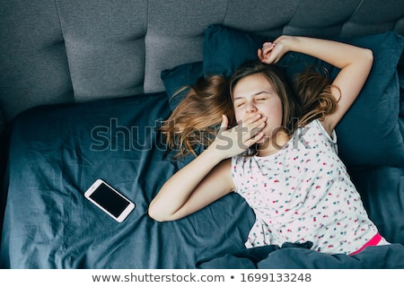 Foto d'archivio: Sleepy Woman In Pajama With Alarm Clock Yawning