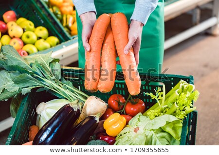 Imagine de stoc: Saleswoman In Organic Supermarket Offering Fresh Carrots