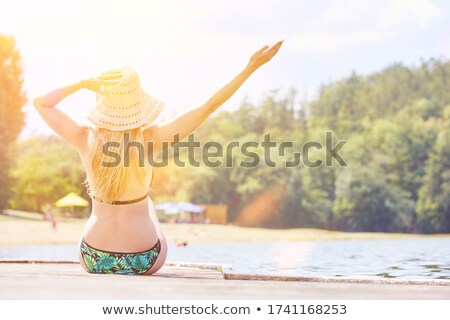 Stock fotó: Young Woman In Bikini Sitting On A Pier At The Lake