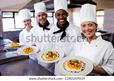 Stok fotoğraf: Group Of Chefs Holding Plate Of Prepared Pasta In Kitchen At Hotel