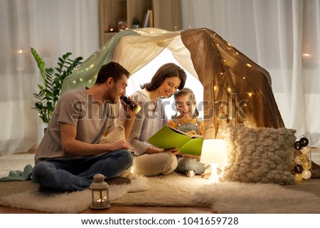 Foto stock: Happy Family Reading Book In Kids Tent At Home
