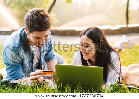 Stok fotoğraf: Happy Young Couple Using Laptop While Lying On Grass