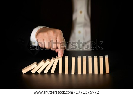 Foto stock: Businessman Stopping Domino Effect - Business Problem Solving Co