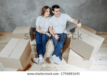 Stok fotoğraf: Cheerful Couple Taking Selfie Among Boxes While Moving