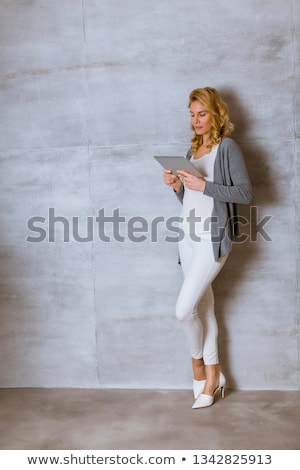 Сток-фото: Young Woman Standing Witd Digital Tablet By Wall