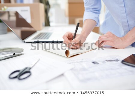 Stock photo: Female Manager Of Online Shop Making Notes On Blank Page Of Notebook