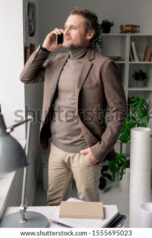 Stockfoto: Confident Mature Architect With Smartphone Standing By Office Window