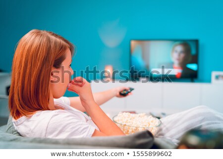 Foto stock: Na · mujer · joven · acostada · en · su · sofá · viendo · la · televisión