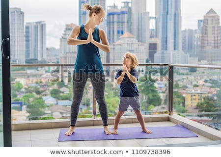 Stock fotó: Mom And Son Are Practicing Yoga On The Balcony In The Background Of A Big City Sports Mom With Kid