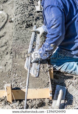 [[stock_photo]]: Pool Construction Worker Working With A Smoother Rod On Wet Conc