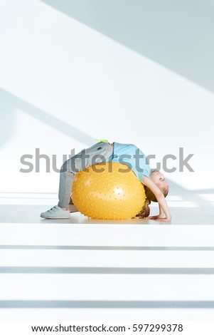 Foto stock: Side View Of Sporty Little Girl Exercising On Fitness Ball