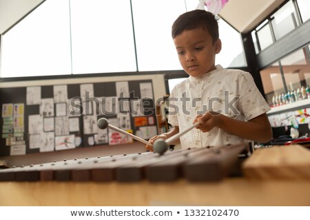 [[stock_photo]]: Front View Of Cute Mixed Race Schoolboy Playing Xylophone In A Classroom At Elementary School