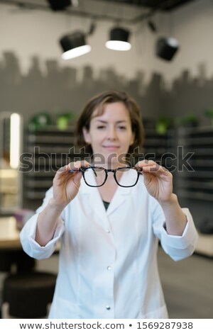 Zdjęcia stock: Professional Female Optometrist In Whitecoat Holding Pair Of New Eyeglasses
