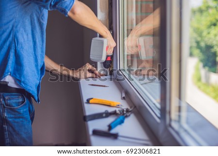 [[stock_photo]]: Man In A Blue Shirt Does Window Installation