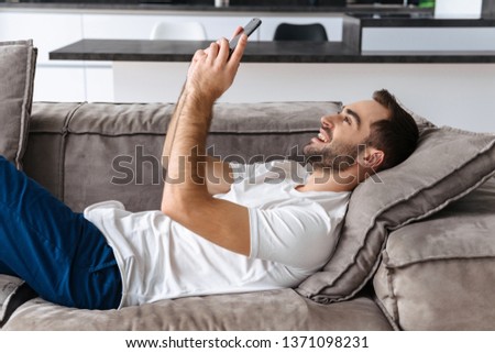 Foto stock: Photo Of Pleased Adult Man 30s In Casual Clothing Typing On Lapt