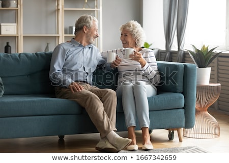 Foto stock: Chatting Women Sitting On A Sofa With Cups In A Living Room