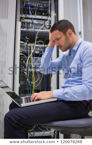 Foto stock: Man Getting Stressed With Laptop Over Servers In Data Center