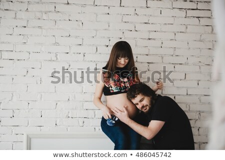 ストックフォト: Young Man Listens To His Pregnant Wife Belly With Amazement