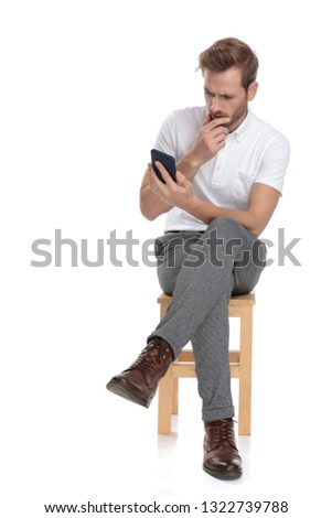 Stock foto: Seated Man Looks Worried While Reading On His Phone