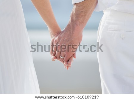 Stock photo: Bride And Groom Lower Bodies Holding Hands Against Blurry Beach
