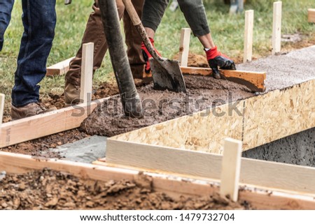 Stock photo: Construction Worker Leveling Wet Cement Into Wood Framing