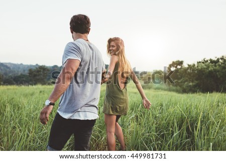 Stockfoto: Rear View Of Young Caucasian Couple Walking Hand In Hand On Rock Near Beach
