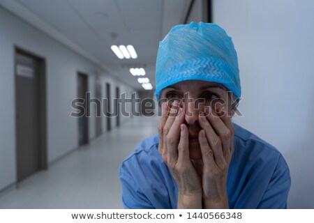 [[stock_photo]]: Portrait Of Tensed Female Surgeon Sitting In Corridor