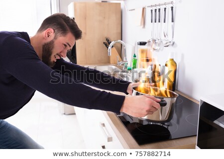 Foto stock: Young Man Looking At Burning Cooking Pot