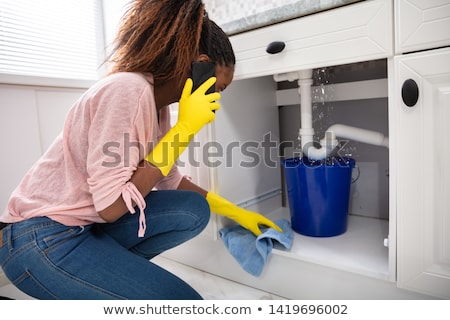 Foto d'archivio: Woman Placing Bucket Under The Sink Pipe