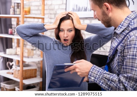 Stockfoto: Technician Showing Invoice To Shocked Woman